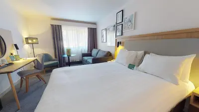 a hotel room with a large white bed and a desk at Holiday Inn Cambridge by IHG in Cambridge