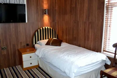 a bedroom with a bed with a wooden wall at Ely Guest House in Ely