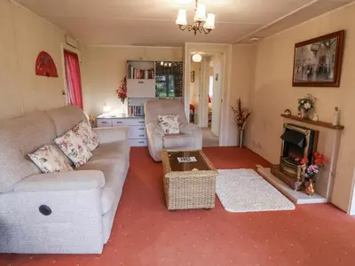 a living room with a couch and a chair and a fireplace at The Lodge in Attleborough