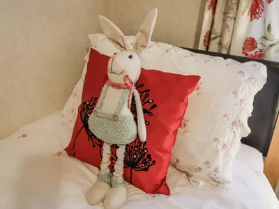 a stuffed rabbit sitting on a bed next to a pillow at The Lodge in Attleborough