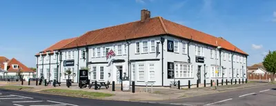 a white building with a red roof on a street at Kingscliff, Holland on Sea in Clacton-on-Sea