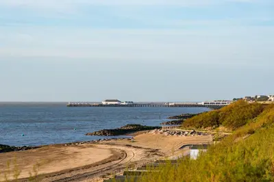 a sandy beach with a pier in the water at Kingscliff, Holland on Sea in Clacton-on-Sea
