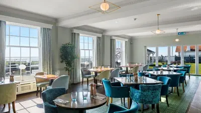 a restaurant with tables and chairs and windows at Kingscliff, Holland on Sea in Clacton-on-Sea