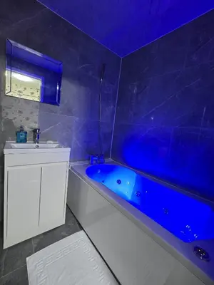 a blue bathroom with a tub and a sink at Zaheer's Hotel in Baldock