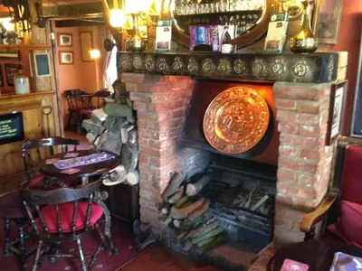 a brick fireplace in a restaurant with a table and chairs at The Olde Windmill Inn in Great Cressingham