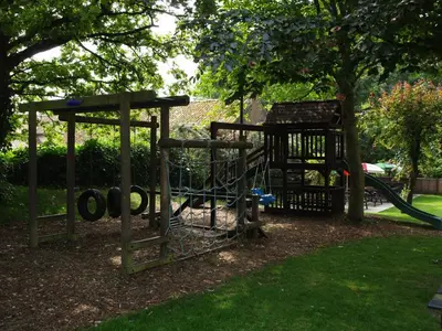 a playground in a park with a tree at The Olde Windmill Inn in Great Cressingham