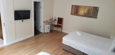 a bedroom with a bed and a desk with a television at Stansted Airport Lodge in Takeley
