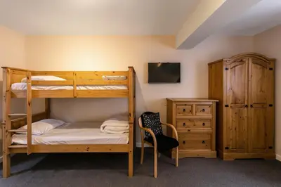 a bedroom with bunk beds and a desk and a chair at Roydon Marina Village Hotel in Roydon
