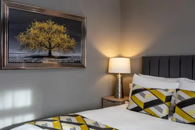 a bedroom with a bed and a picture of a tree at Roydon Marina Village Hotel in Roydon