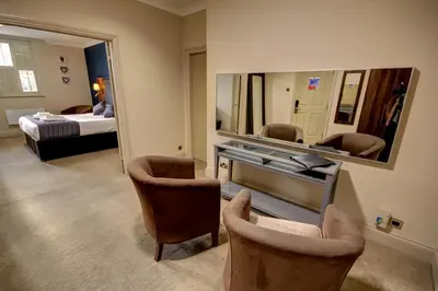 a room with a mirror and two chairs and a bed at The Rochford Hotel in Southend-on-Sea