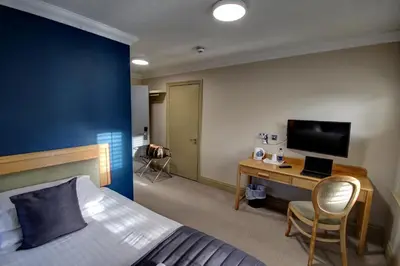 a bedroom with a bed and a desk with a television at The Rochford Hotel in Southend-on-Sea