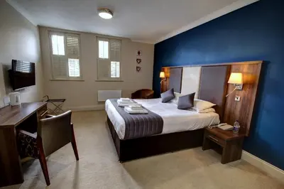 a bedroom with a bed with a desk and a blue wall at The Rochford Hotel in Southend-on-Sea