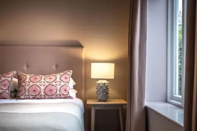 a bedroom with a bed with a lamp and a window at The Crown Inn in Stoke by Nayland