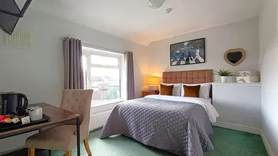a bedroom with a bed and a desk and a window at Stansted Lodge Elsenham in Elsenham