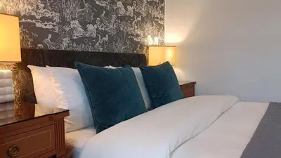 a bedroom with a bed with blue and white pillows at Stansted Lodge Elsenham in Elsenham