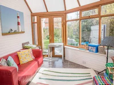 a living room with a red couch in front of a lighthouse at Honeybee Cottage, Orford in Orford