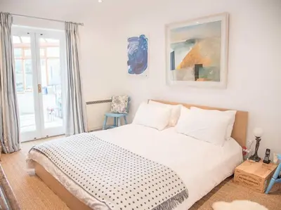 a white bedroom with a bed and a window at Honeybee Cottage, Orford in Orford