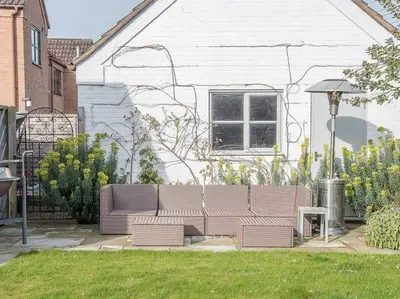 a couch sitting in a yard next to a house at Honeybee Cottage, Orford in Orford