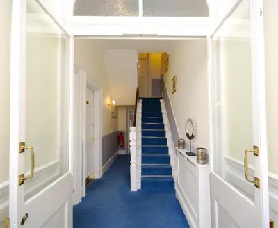 a hallway with blue carpeted floors and stairs at Pier View Self Catering Luxury Apartments in Southend-on-Sea