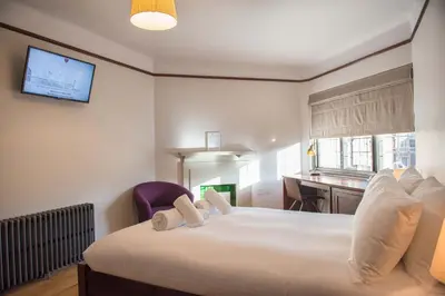 a bedroom with a large bed with a tv on the wall at West Court- Jesus College in Cambridge