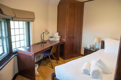 a hotel room with a desk and a bed at West Court- Jesus College in Cambridge