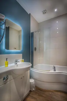 a bathroom with a white tub and a sink and a bath tub at The Golden Lion Hotel, St Ives, Cambridgeshire - The Coaching Inn Group in St Ives