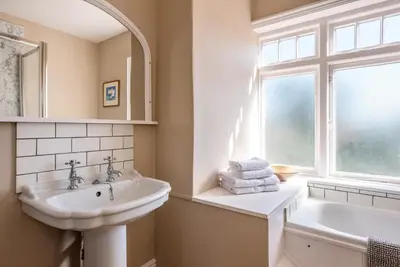 a white bathroom with a sink and a window at Hillcrest, Aldeburgh in Aldeburgh