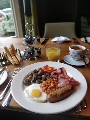 a plate of breakfast food on a wooden table at The White Hart in Great Yeldham