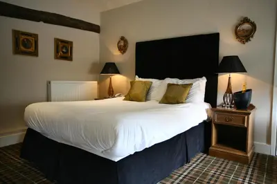 a bedroom with a large bed with white sheets and pillows at The White Hart in Great Yeldham