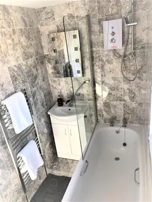 a bathroom with a shower and a tub and a sink at Guineas House in Newmarket