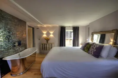 a bedroom with a large white bed and a tub at Strattons in Swaffham