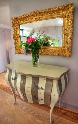 a vase of flowers on a table in front of a mirror at Strattons in Swaffham