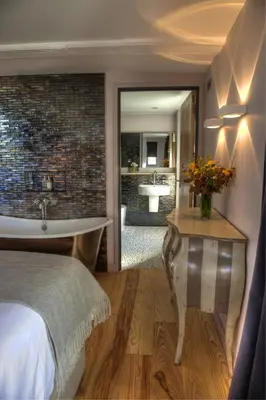 a bedroom with a bed and a bathroom with a tub at Strattons in Swaffham