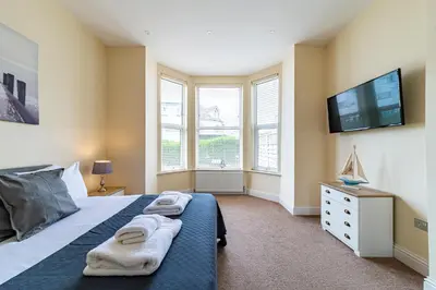 a bedroom with a bed and a tv and windows at Greyfriars in Clacton-on-Sea