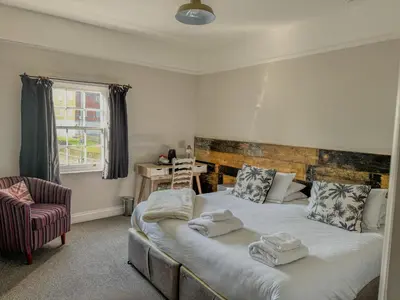 a bedroom with a large bed and a chair at The White Horse Hotel in Leiston
