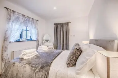 a bedroom with a bed with white sheets and a window at Highgate Annexe in Takeley