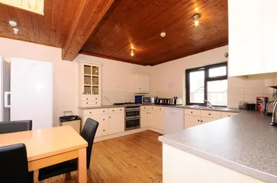 a large kitchen with white cabinets and a wooden ceiling at The Rathmore in Cambridge