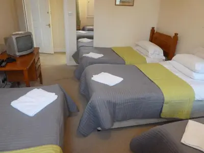 a room with four beds with a television and a desk at The Rathmore in Cambridge