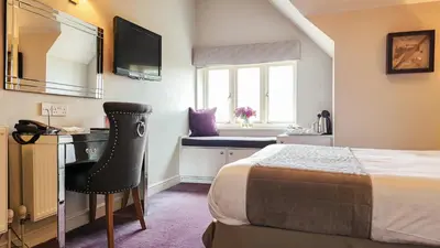 a bedroom with a bed and a desk and a mirror at The Pheasant Public House & Hotel in Gestingthorpe