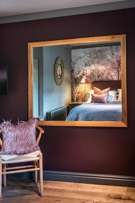 a mirror in a room with a bed and a chair at The Cricketers Clavering in Clavering