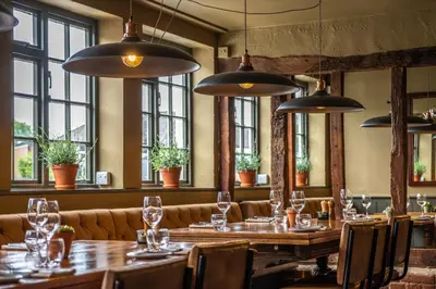 a restaurant with wooden tables and chairs and windows at The Cricketers Clavering in Clavering