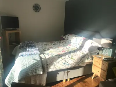 a bedroom with a bed and a clock on the wall at Corner House Luxury BnB in Little Dunmow