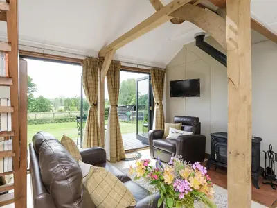 a living room with a leather couch and a fireplace at Toad Hall Cottage in Earls Colne