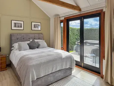 a bedroom with a bed and a sliding glass door at Toad Hall Cottage in Earls Colne