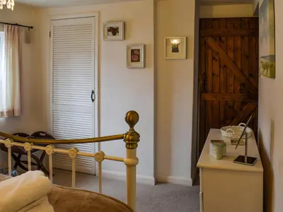 a bedroom with a bed and a wooden door at Lavenham Red Brick Cottage in Lavenham