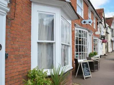 a white window on a brick building next to a street at Lavenham Red Brick Cottage in Lavenham