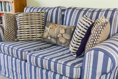 a blue and white striped couch with pillows on it at 4 Bell Lodge, Thorpeness in Thorpeness