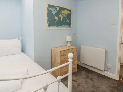 a bedroom with a white bed and a wooden cabinet at Ploughman's in Eye