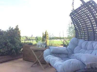 a blue couch sitting on a patio with a table at Kingfisher Nook at Waveney Farm in Hoxne