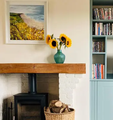 a vase with sunflowers sitting on top of a fireplace at Kingfisher Nook at Waveney Farm in Hoxne